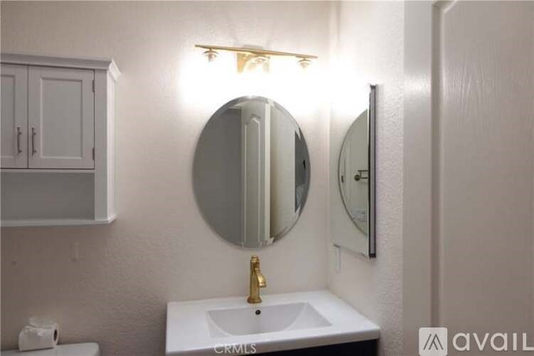 A bathroom with a sink, mirror, and cabinet.