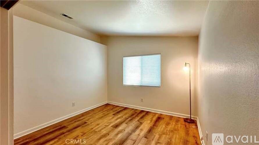 A room with wooden flooring and a window with blinds.
