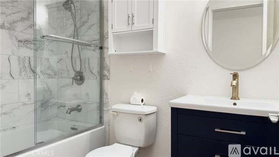 A bathroom with a marble shower, toilet, and sink.