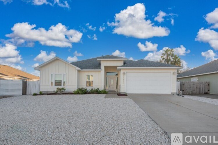 A house with a gravel driveway and a clear blue sky above.