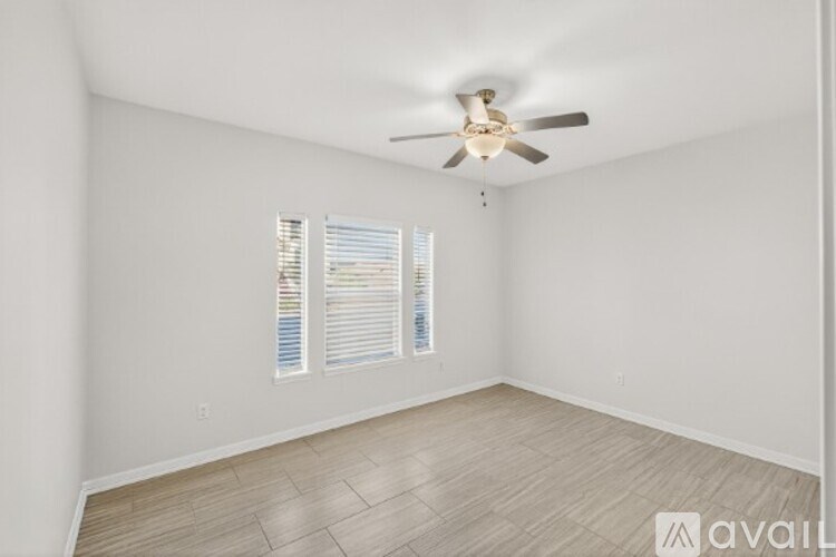 A room with a ceiling fan and a window with blinds.