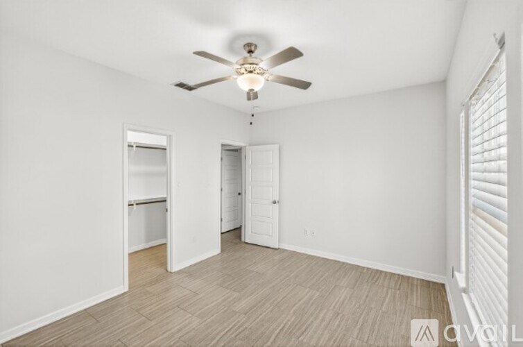 A room with a ceiling fan and light fixture, and a window with blinds.