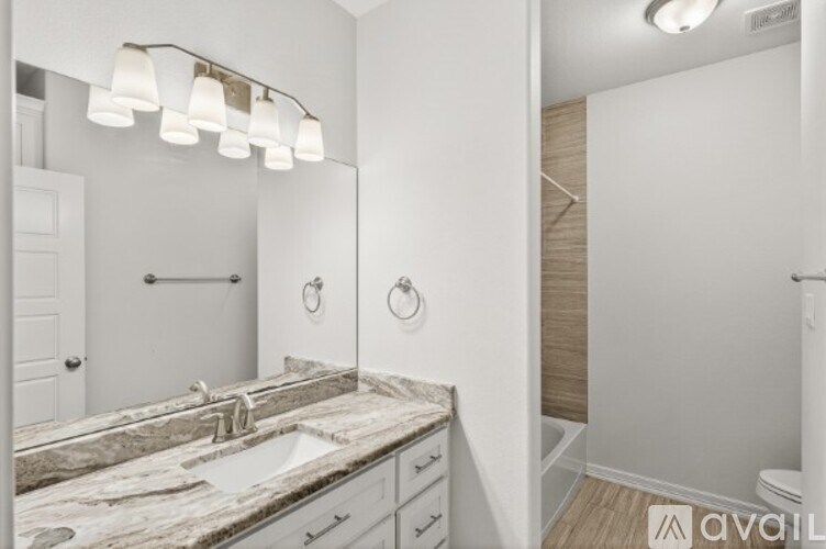 A bathroom with a marble countertop and a mirror above the sink.