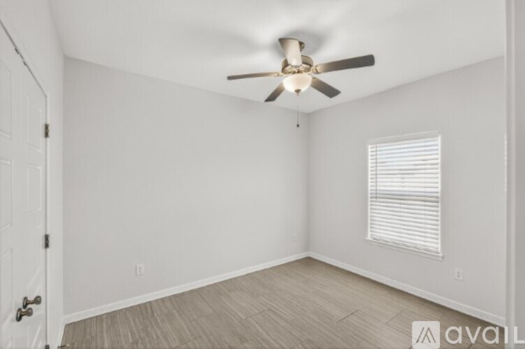 A room with a ceiling fan and a window with blinds.