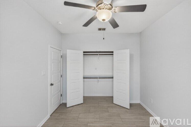 A room with a ceiling fan and a white door.