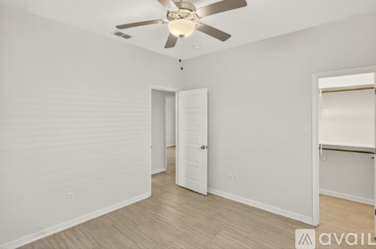 A room with a ceiling fan and a doorway leading to another room.