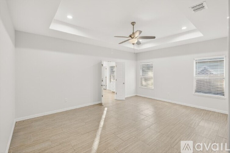 A room with a ceiling fan and a door in the background.