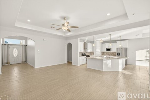 A spacious kitchen and living room with a ceiling fan and lighting fixtures.