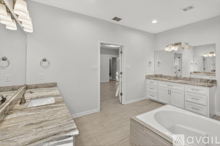 A bathroom with a marble countertop and a large tub.