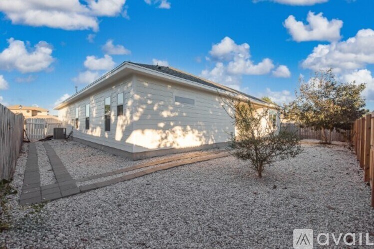 A house with a gravel driveway and a small tree in front.