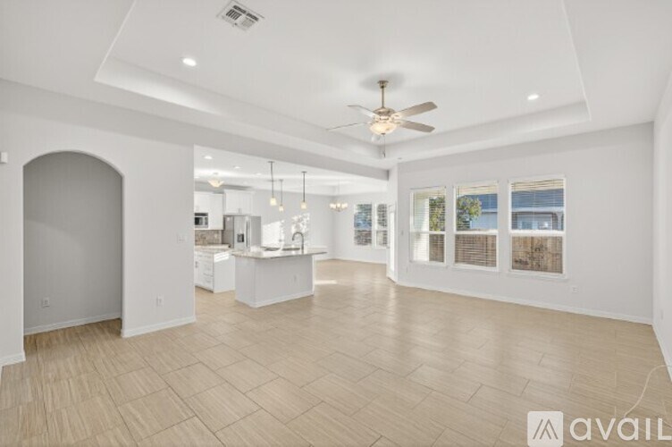 A spacious living room with a ceiling fan and lighting fixtures.