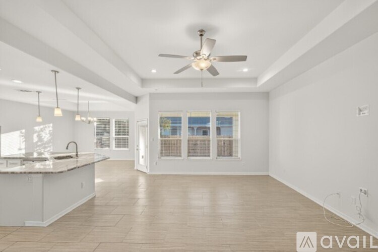 A spacious kitchen with a fan and a view of the outside through the window.