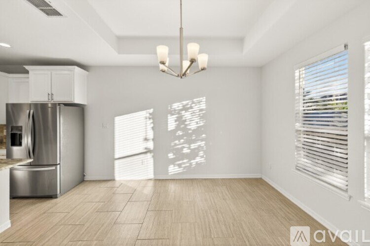 A kitchen with a refrigerator, cabinets, and a pendant light.