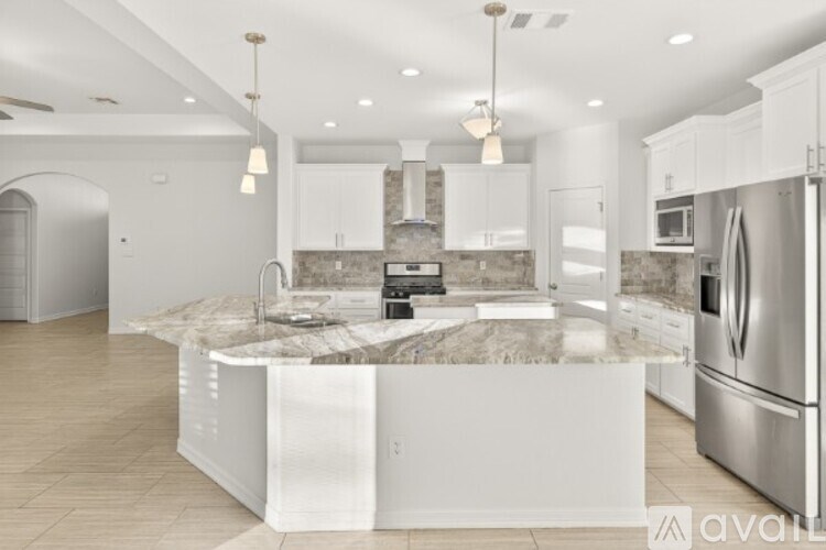 A modern kitchen with a marble island and stainless steel appliances.