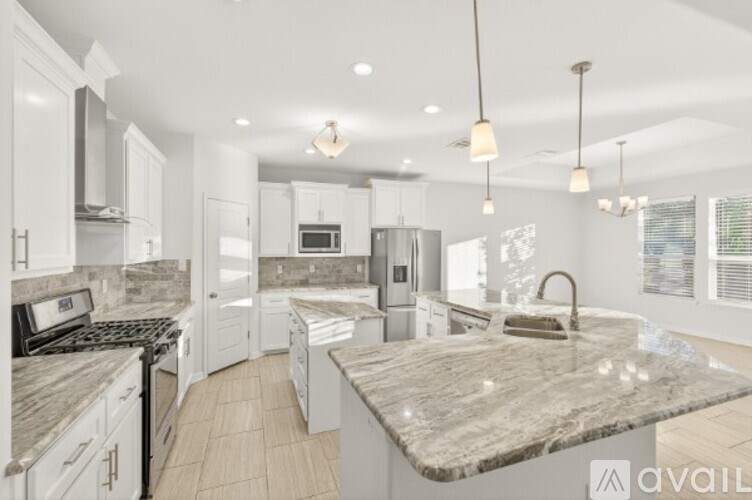 A modern kitchen with a marble countertop and stainless steel appliances.
