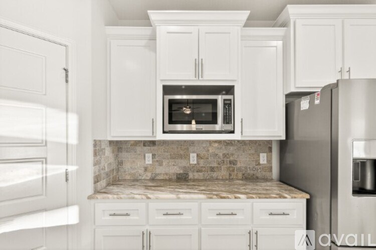 A kitchen with white cabinets and a granite countertop.