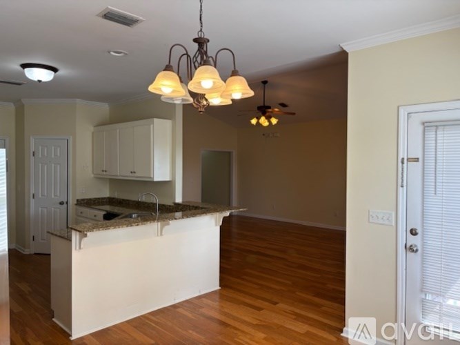 A kitchen with a white island and a chandelier hanging from the ceiling.
