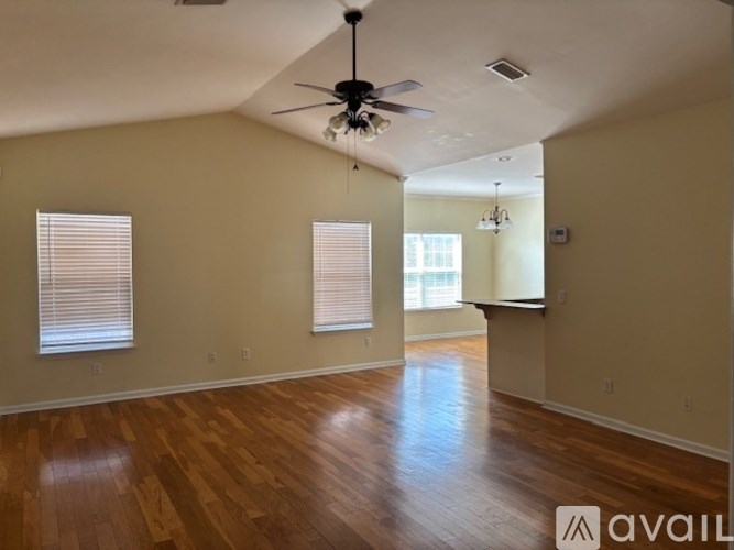 A spacious room with wooden floors and a ceiling fan.