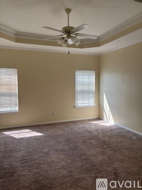 A room with a ceiling fan and two windows.