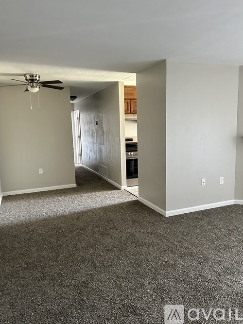 A room with a ceiling fan and carpeted floor.