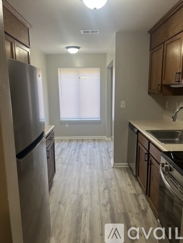 A kitchen with a refrigerator, sink, and cabinets.