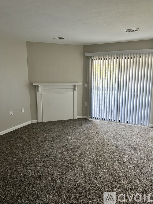 A room with a carpet floor and a sliding door.