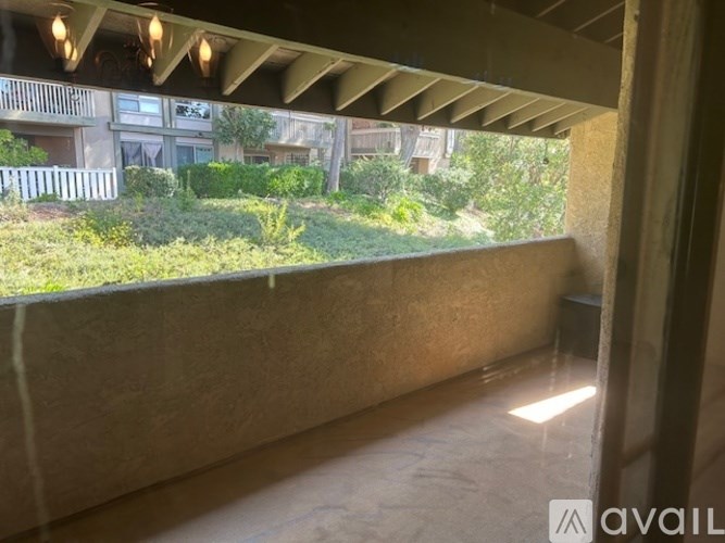 A balcony with a view of a green yard and a building.