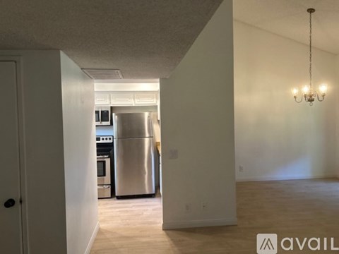 A kitchen with a stainless steel refrigerator and a chandelier hanging from the ceiling.