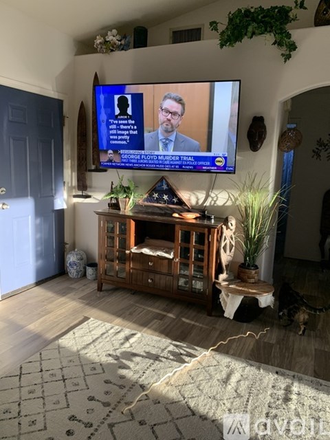 A living room with a television on the wall showing a news program.