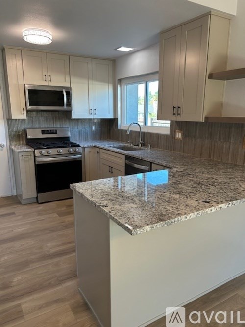 A kitchen with a granite countertop and wooden flooring.