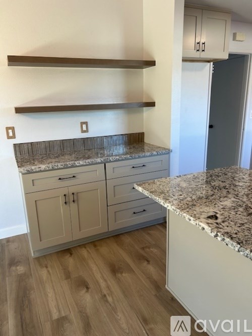 A kitchen with a granite countertop and wooden flooring.