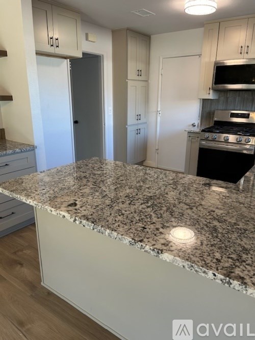 A kitchen with granite countertops and white cabinets.