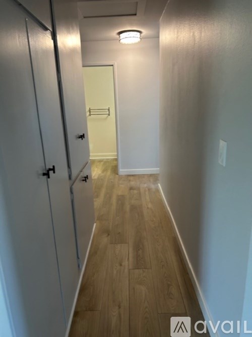 A long hallway with wood floors and white walls.