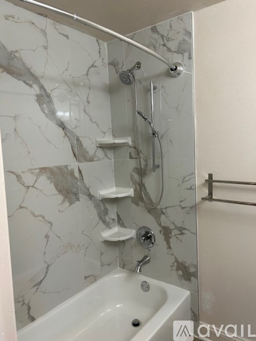 A bathroom with marble walls and a white bathtub.