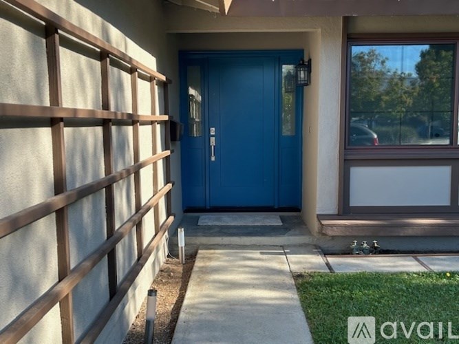 A blue door is on the left side of a white wall with a window on the right.