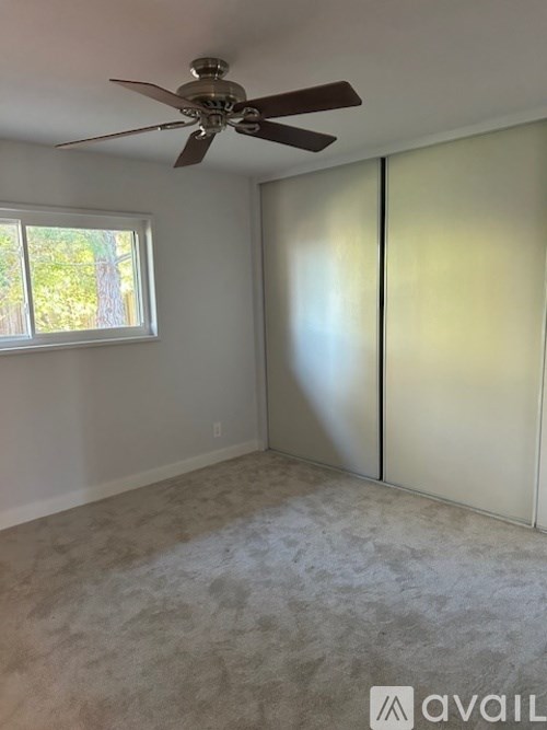 A room with a ceiling fan and sliding doors.
