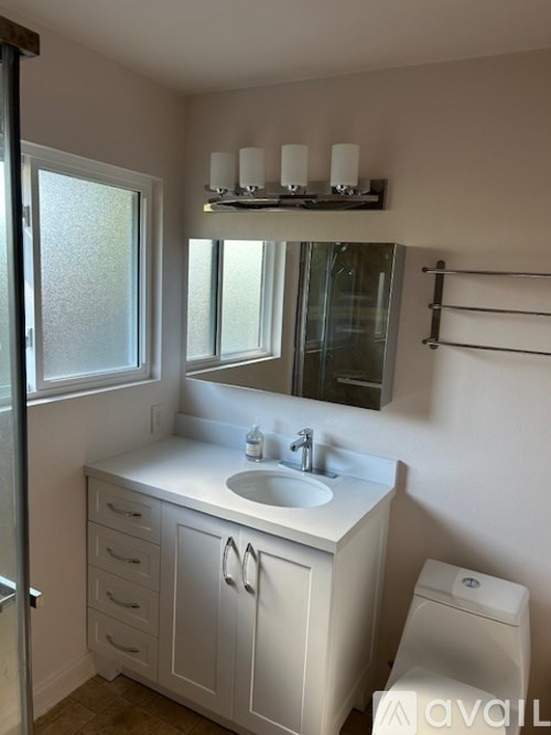 A bathroom with a sink, toilet, and mirror.