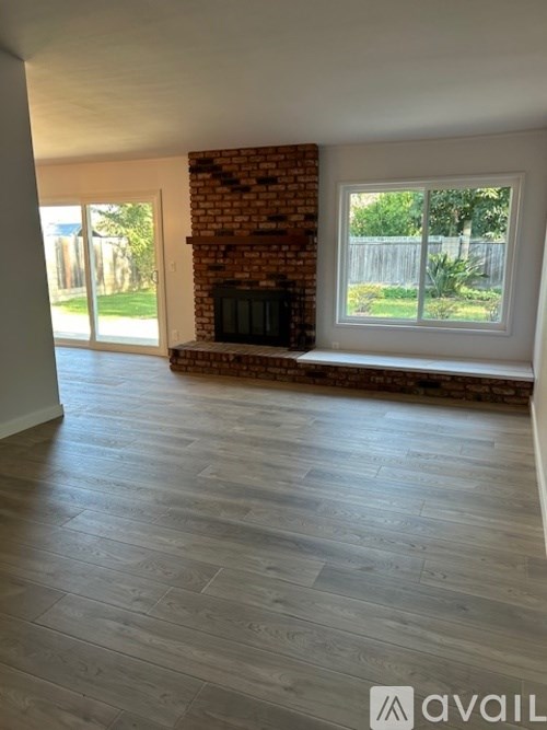 A room with a brick fireplace and wooden flooring.