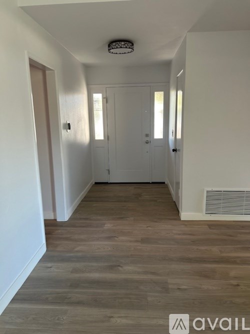 A hallway with wooden floors and white walls.