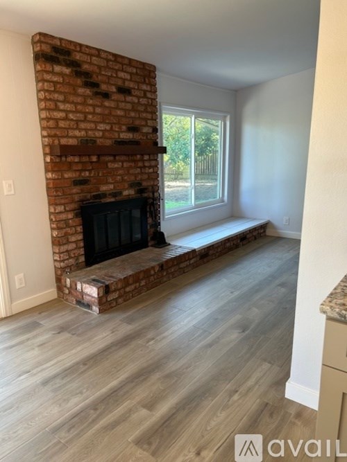 A room with a brick fireplace and wooden flooring.