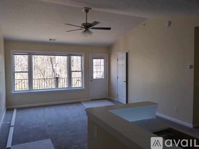 A room with a ceiling fan and a window overlooking a deck.