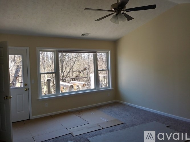A room with a ceiling fan and a large window overlooking a deck.