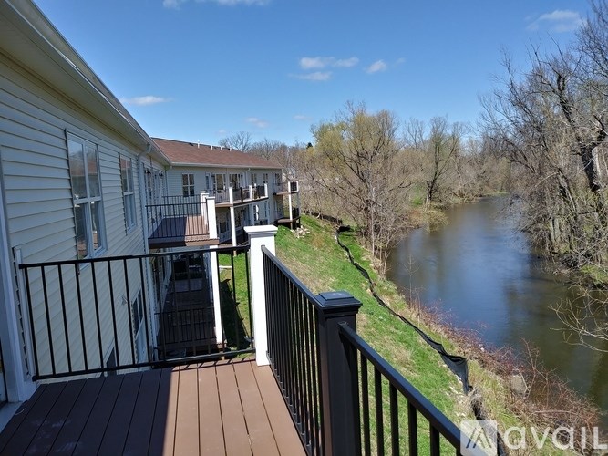 A balcony overlooks a river with a building in the background.