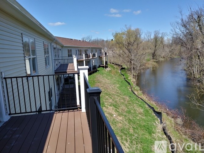 A balcony overlooks a river with houses on the left.