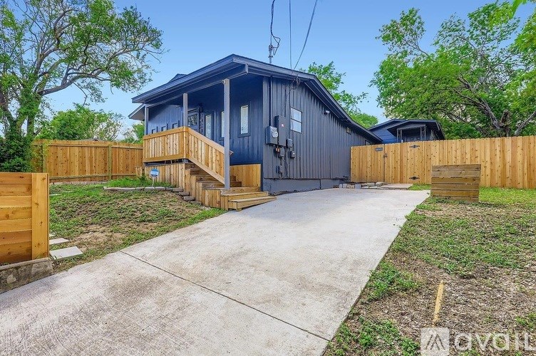 A blue house with a wooden fence and a concrete driveway.