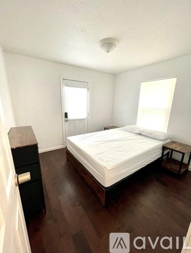 A bedroom with a bed, nightstand, and a window.