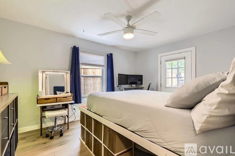 A bedroom with a bed, a dresser, and a window with blue curtains.
