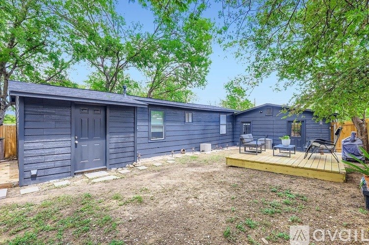 A blue house with a wooden deck and trees in the background.