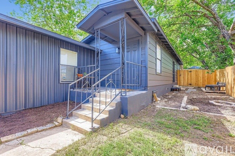 A blue house with a metal staircase leading to a balcony.