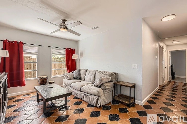 A living room with a grey couch, a coffee table, and a fan.